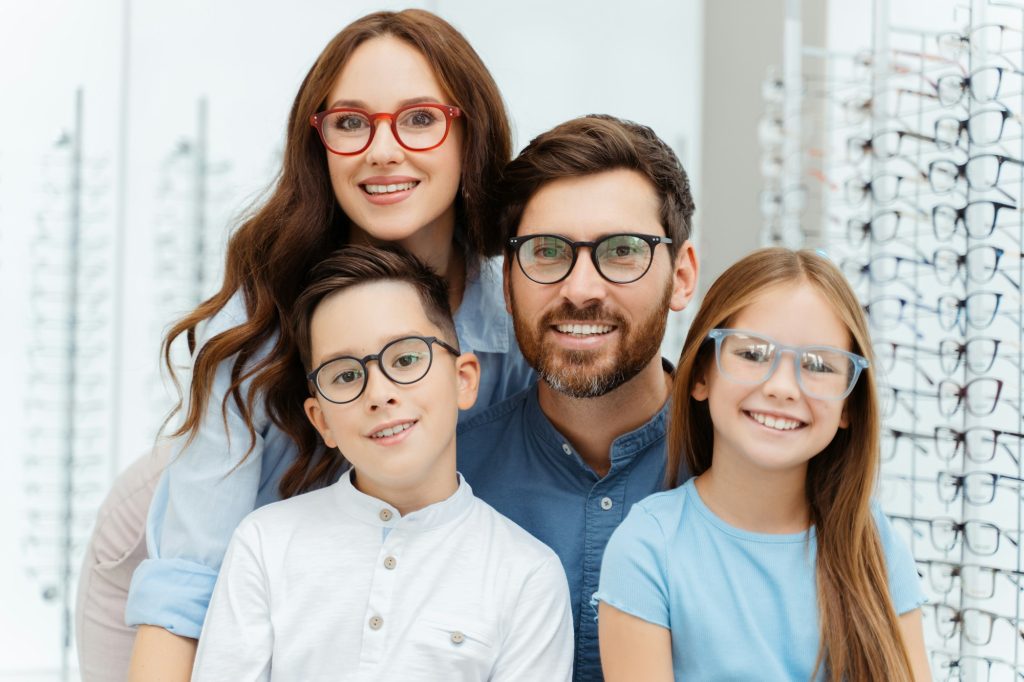 Happy family choosing eyeglasses frames in optical shop